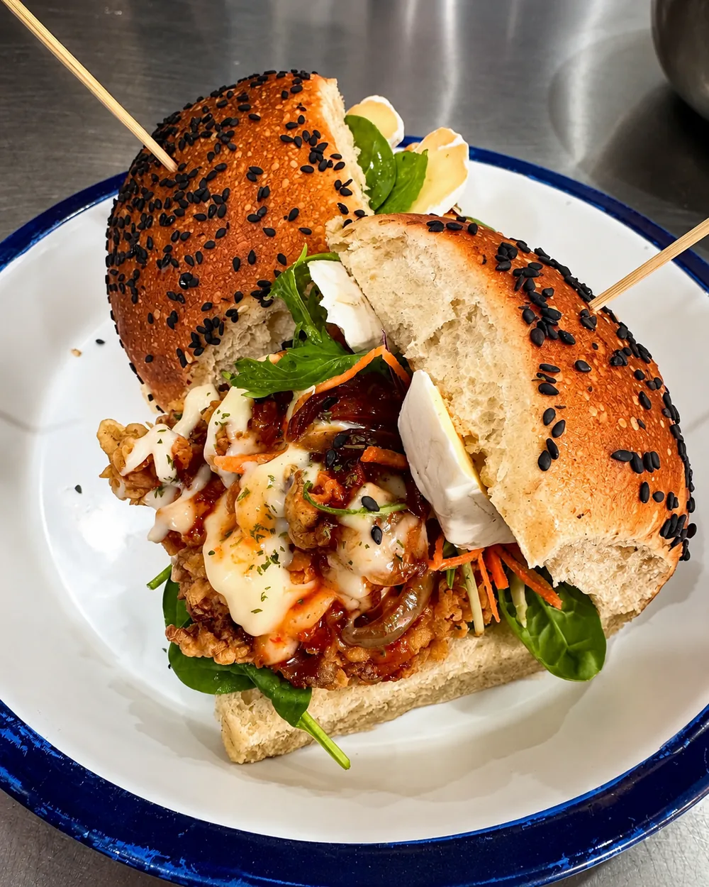 A generously filled sesame-topped sandwich on a blue-rimmed plate