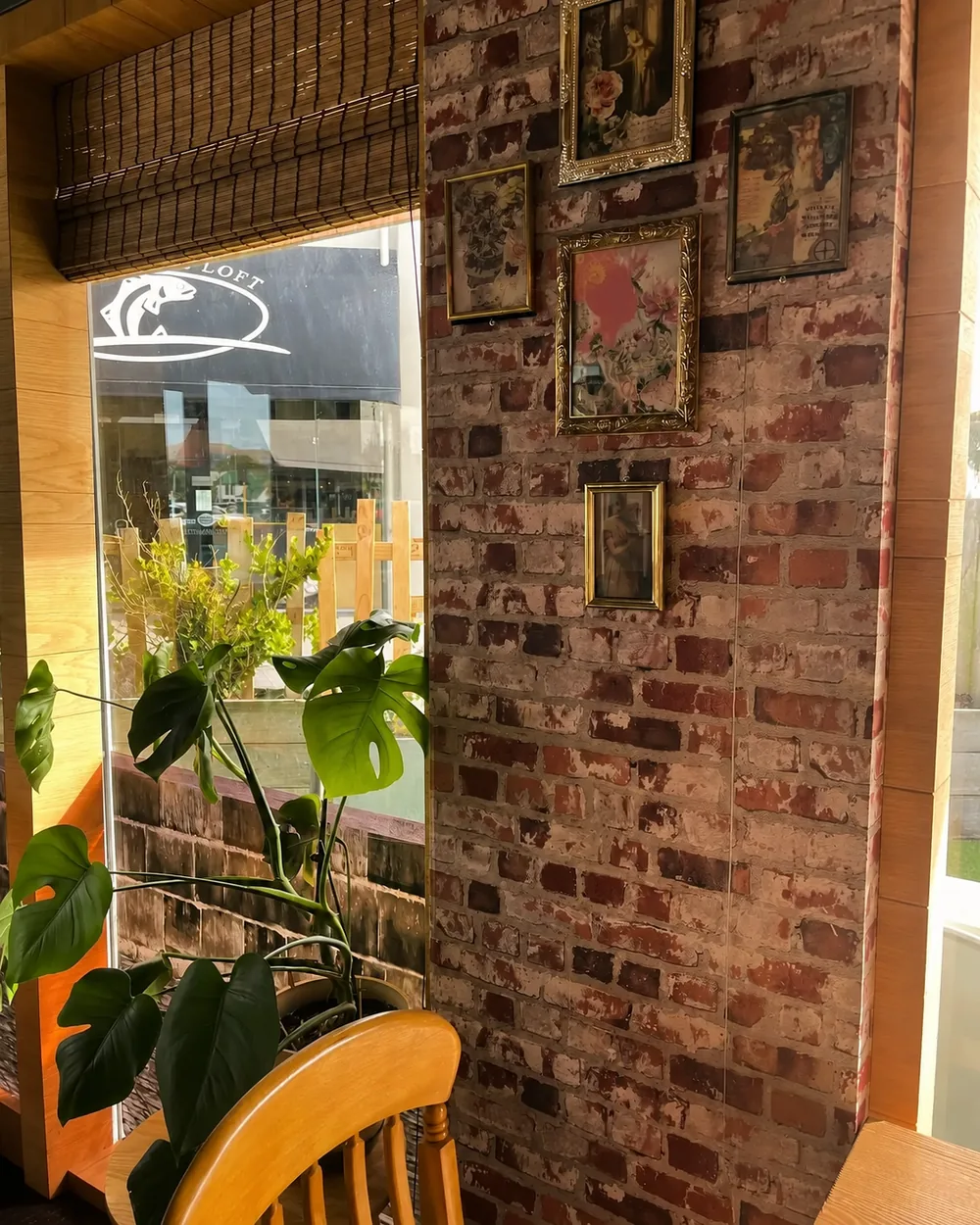 Wooden chairs, potted plants and a brick wall beside N’Joy’s front window